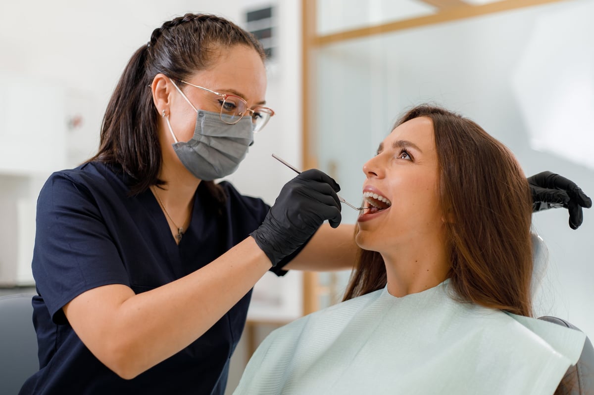Higienista dental examinando cuidadosamente los dientes de un paciente durante una revisión de rutina en una clínica