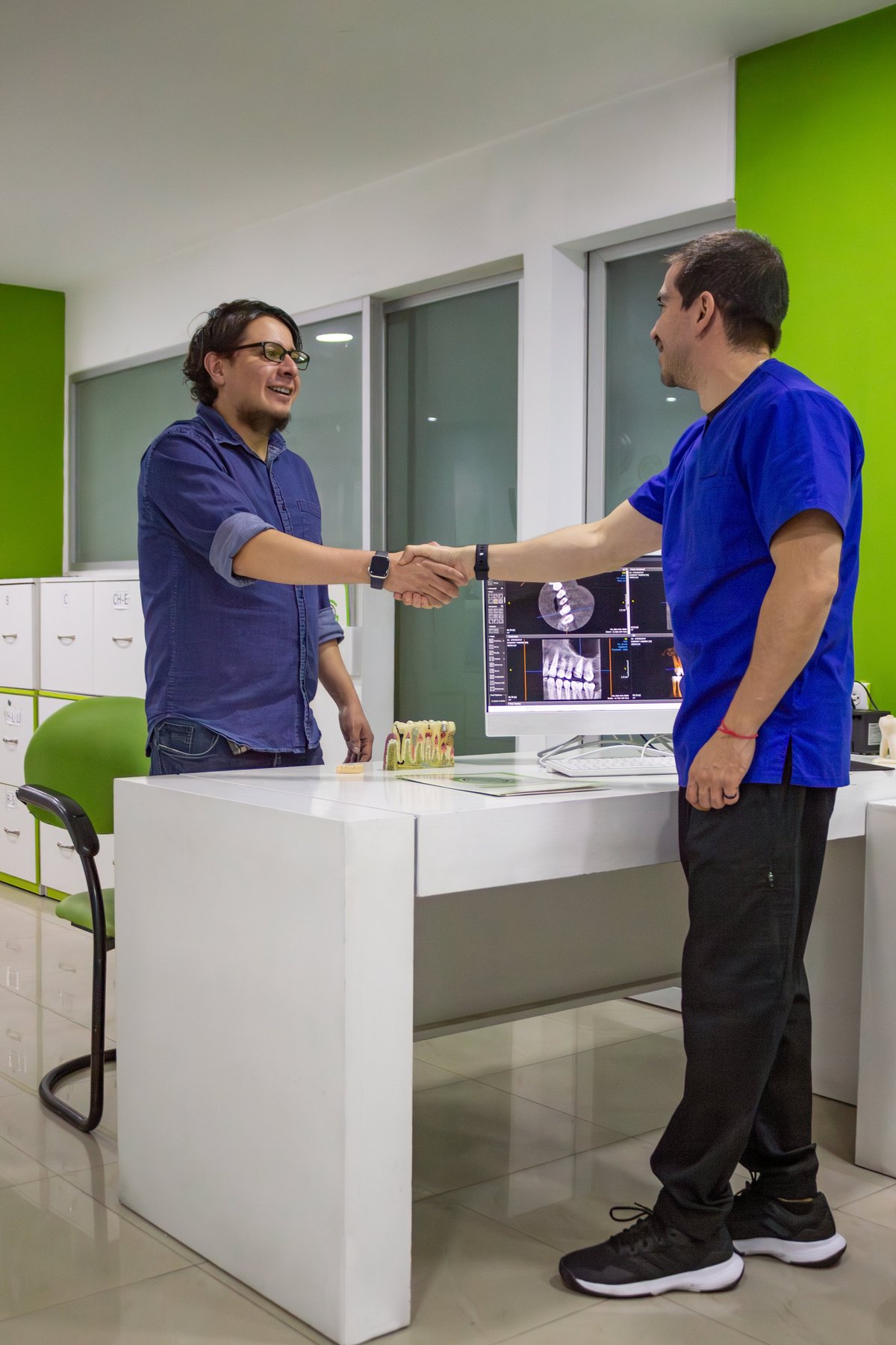 Dentist and patient shaking hands, concluding a successful dental consultation and treatment plan