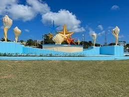 Buddhist temple with golden spires behind blue decorative fence and green lawn