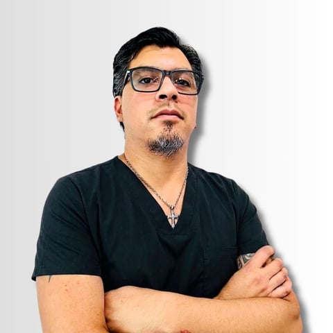 Man with glasses and goatee wearing black v-neck shirt, arms crossed, against white background