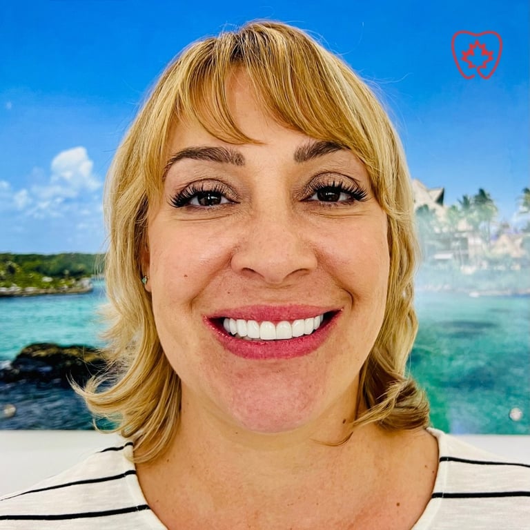 Woman with blonde wavy hair and bangs smiling at camera with tropical beach and turquoise water in background