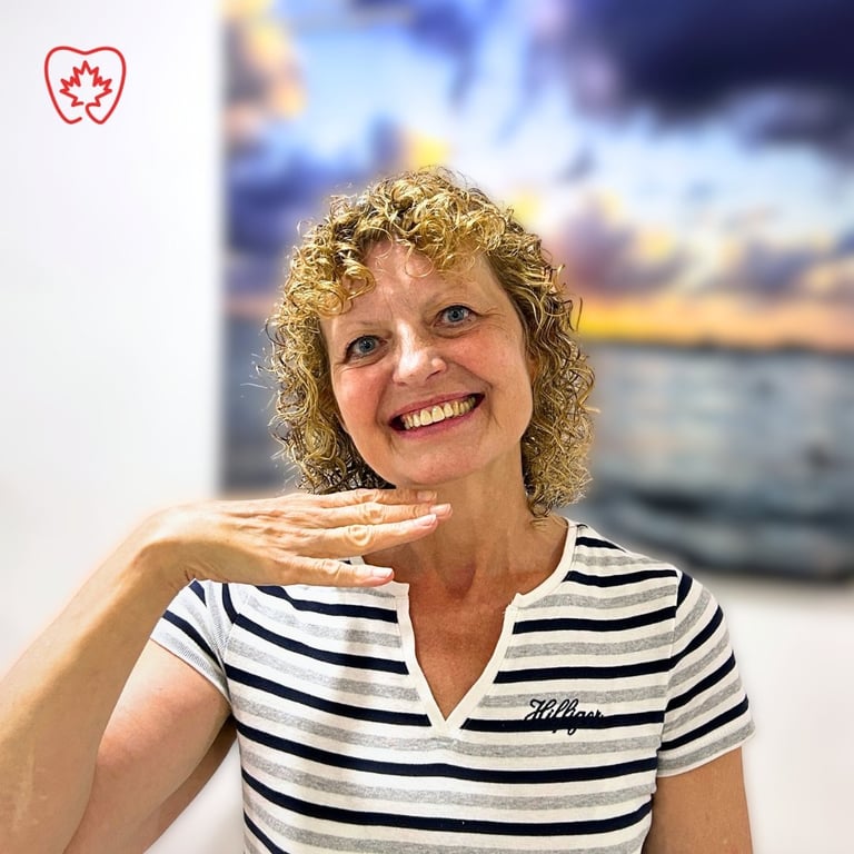 Woman with curly blonde hair smiling at camera, wearing striped navy and white shirt, with sunset landscape photo in background