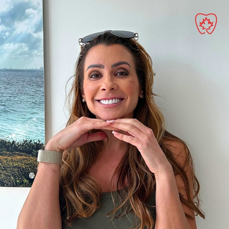 Woman with long brown hair smiling at camera with hands near face, sunglasses on head, beach photo visible behind her